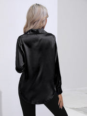 Black satin tie-front blouse with long sleeves and a curved hem.
