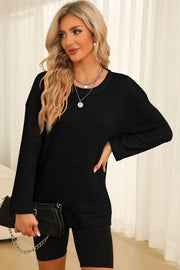 Black waffle knit oversized top with crewneck and slit hem detail.