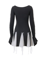 Black mini dress with long bell sleeves and a layered skirt featuring white fabric panels tied with bows.