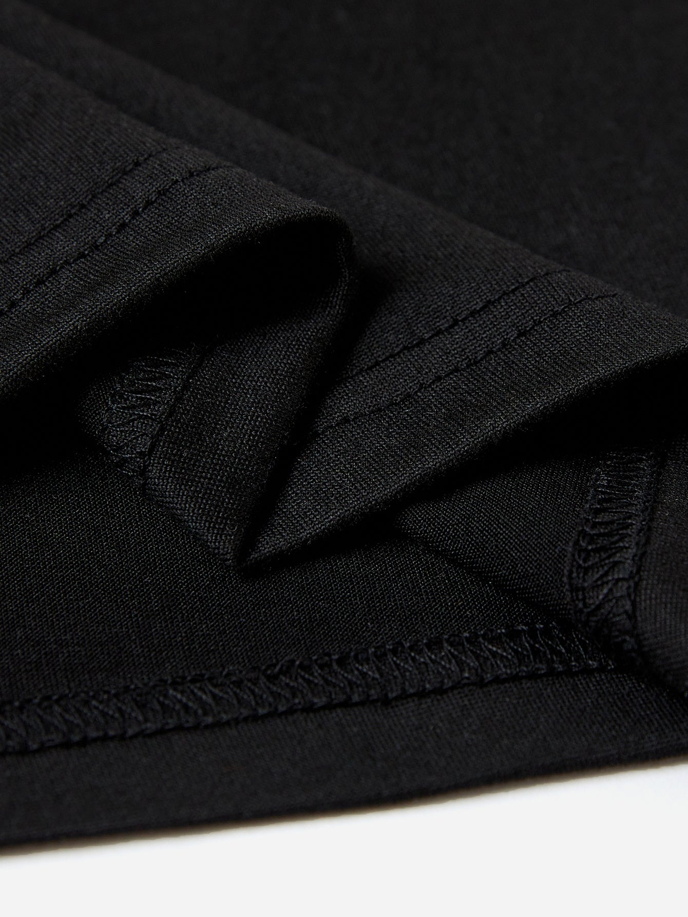 Black t-shirt detail showing textured fabric and double-stitched seams.