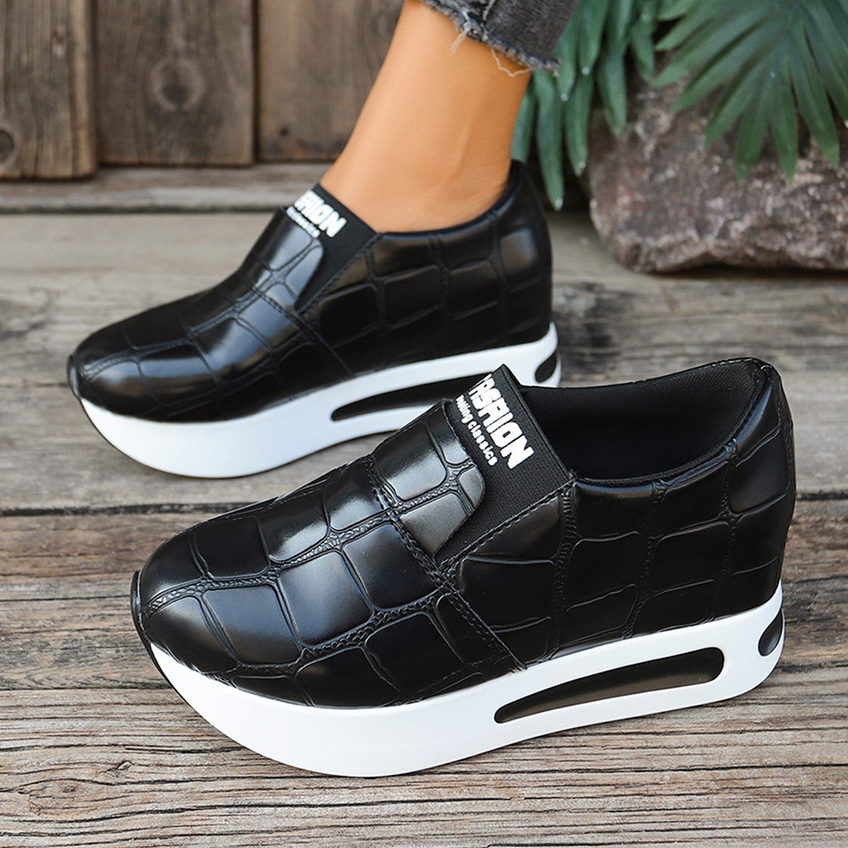 Black crocodile pattern slip-on platform shoes with white soles.