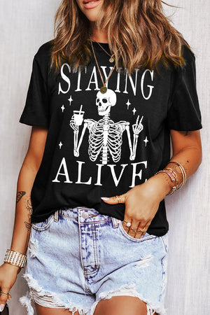 Black graphic t-shirt with skeleton holding drink and peace sign, "Staying Alive" text