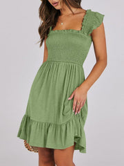Smocked ruffle hem mini dress in sage green with square neckline and flutter sleeves.