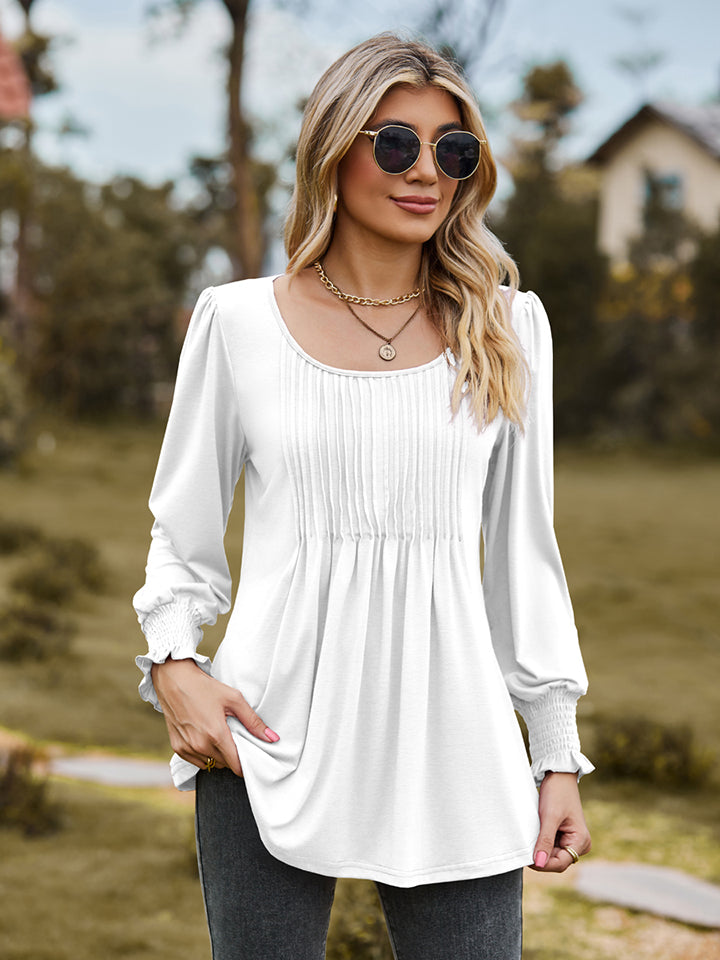 White peplum blouse with gathered yoke and smocked cuffs.