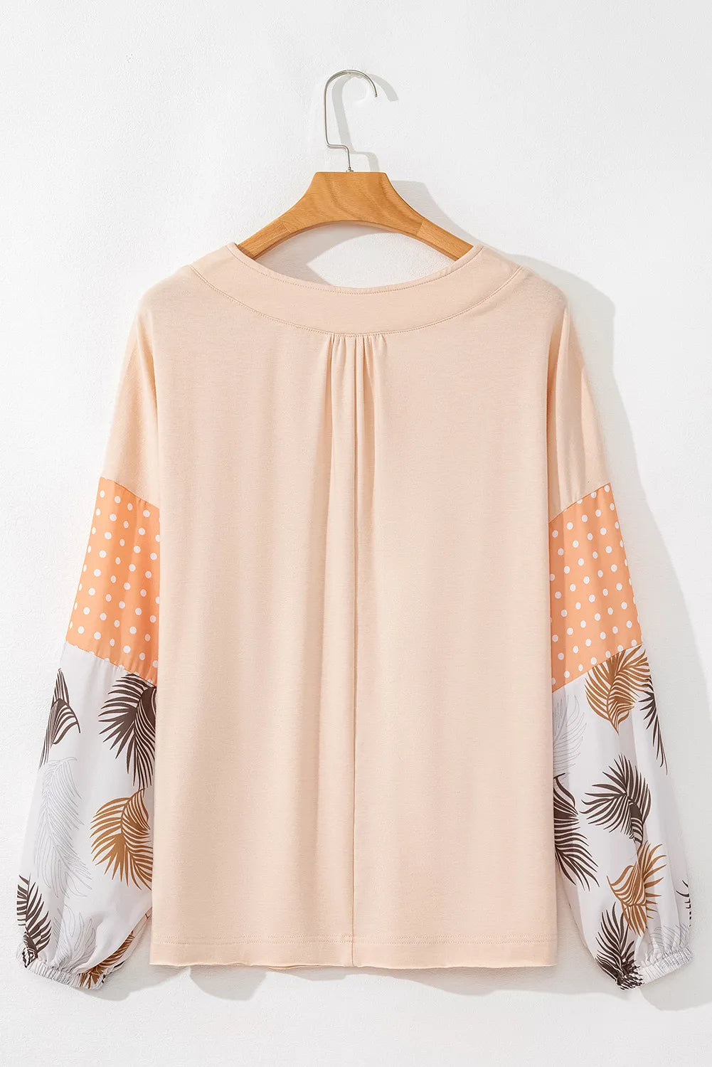 Peach blouse with gathered V-neck and patchwork sleeves featuring polka dots and leaf print.