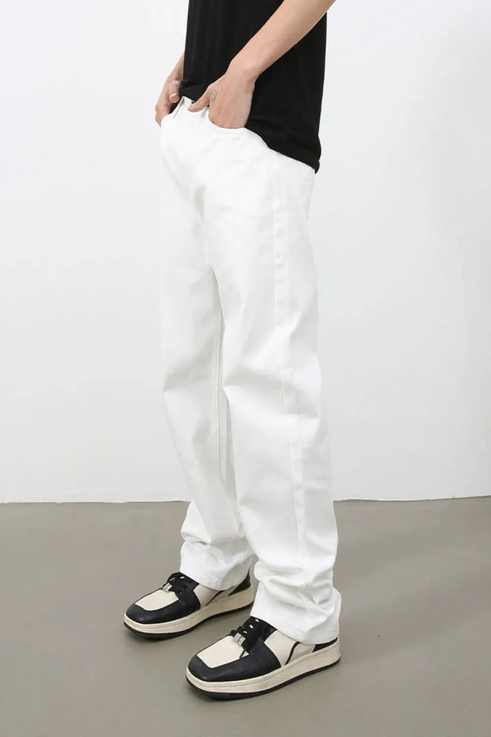 Relaxed ivory denim jeans with a straight leg, styled with a black t-shirt and two-tone sneakers.