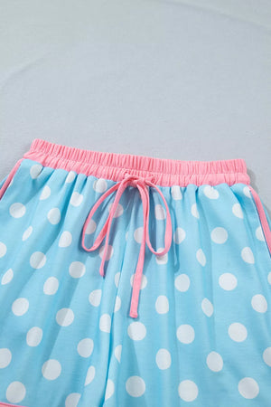 Polka dot pajama shorts in pastel blue polyester with pink drawstring and contrast trim.