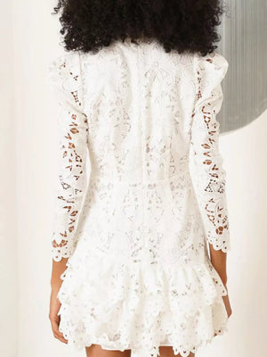 White floral lace mini dress with mock neck, puff sleeves, and tiered ruffle hem.