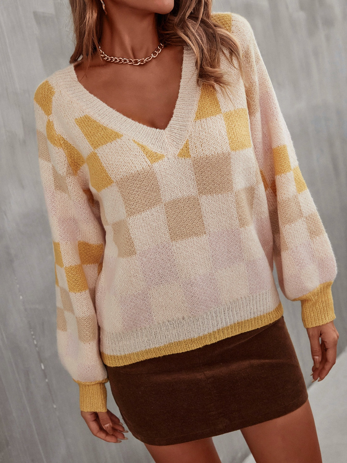 Geometric puff sleeve v-neck knit sweater in cream with yellow checkerboard pattern.