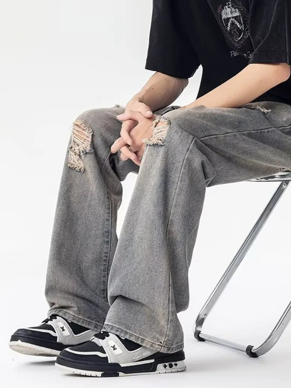 Men's grey loose fit jeans with distressed knee details and a relaxed cut.