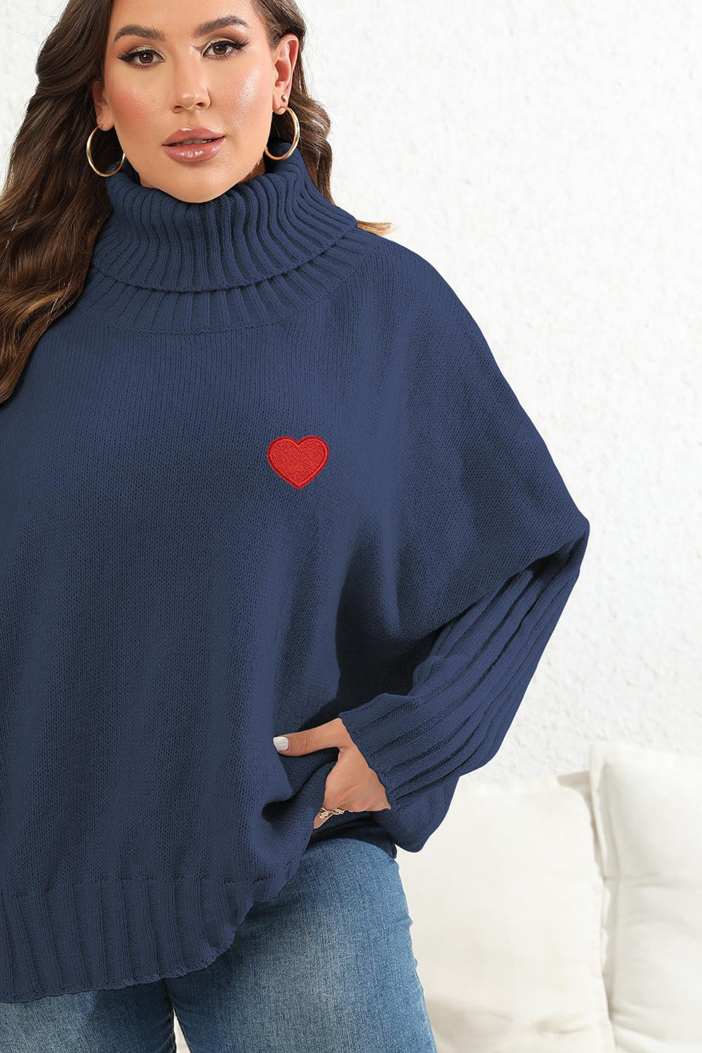 Navy turtleneck sweater with red heart appliqué and batwing sleeves.