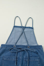 Denim wide-leg overalls in medium wash with adjustable straps and drawstring waist.