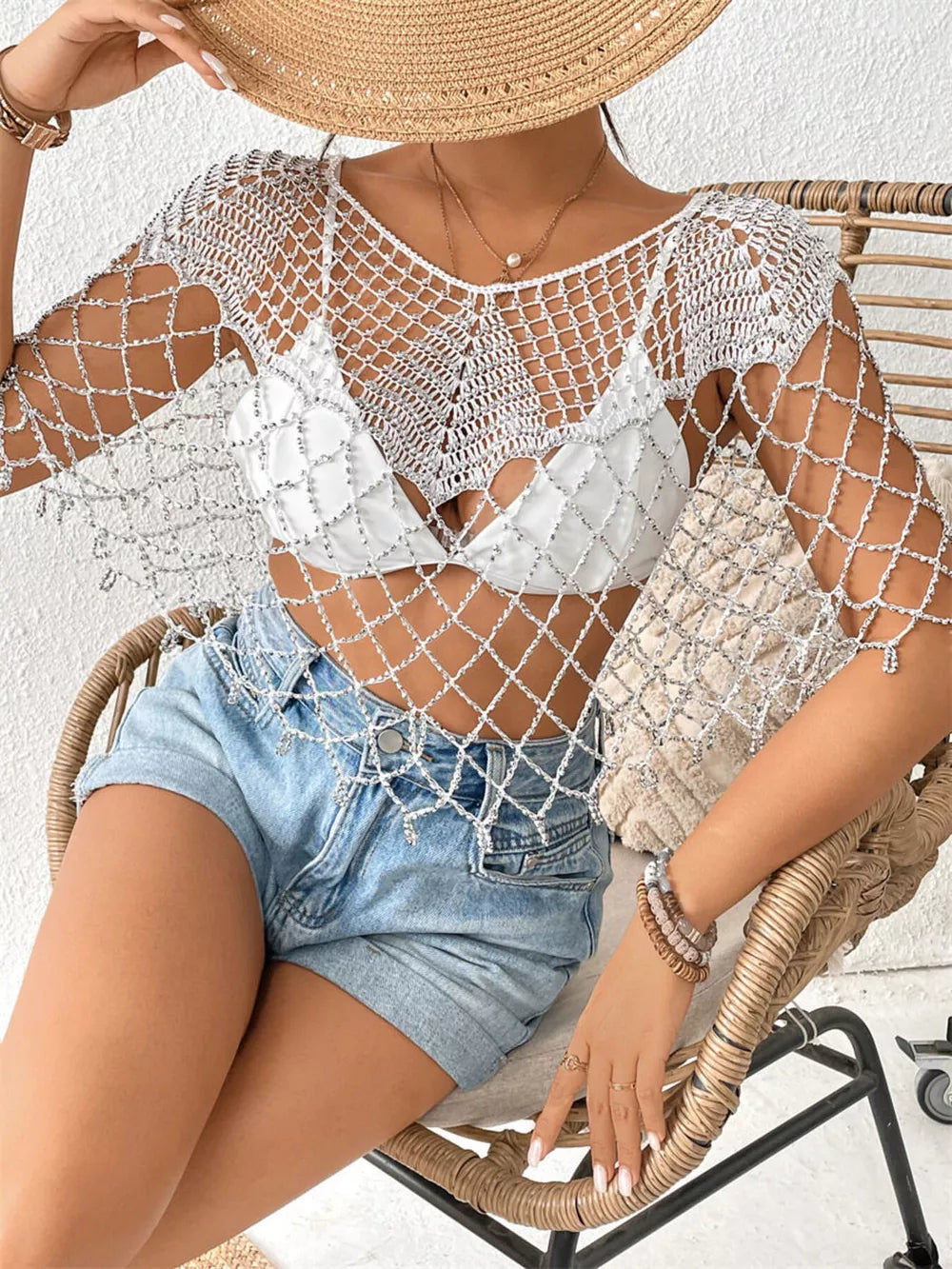 White crochet cardigan with metallic threads and fringe detail, styled over a bikini top.