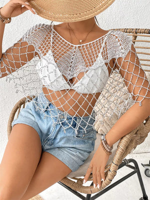 White crochet cardigan with metallic threads and fringe detail, styled over a bikini top.