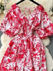 Tropical print smocked wide-leg romper in Scarlet with puff sleeves and tie neck.