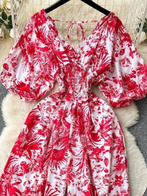 Tropical print smocked wide-leg romper in Scarlet with puff sleeves and tie neck.