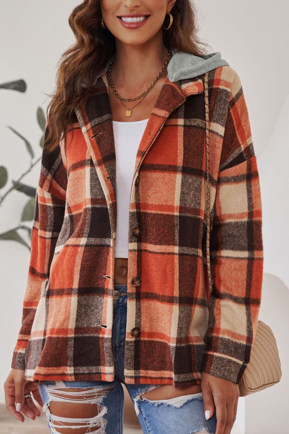 Plaid hooded shacket in orange, tan, and brown with button front and relaxed fit.