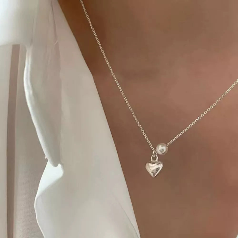 Delicate silver heart pendant necklace with pearl accent on a fine chain.
