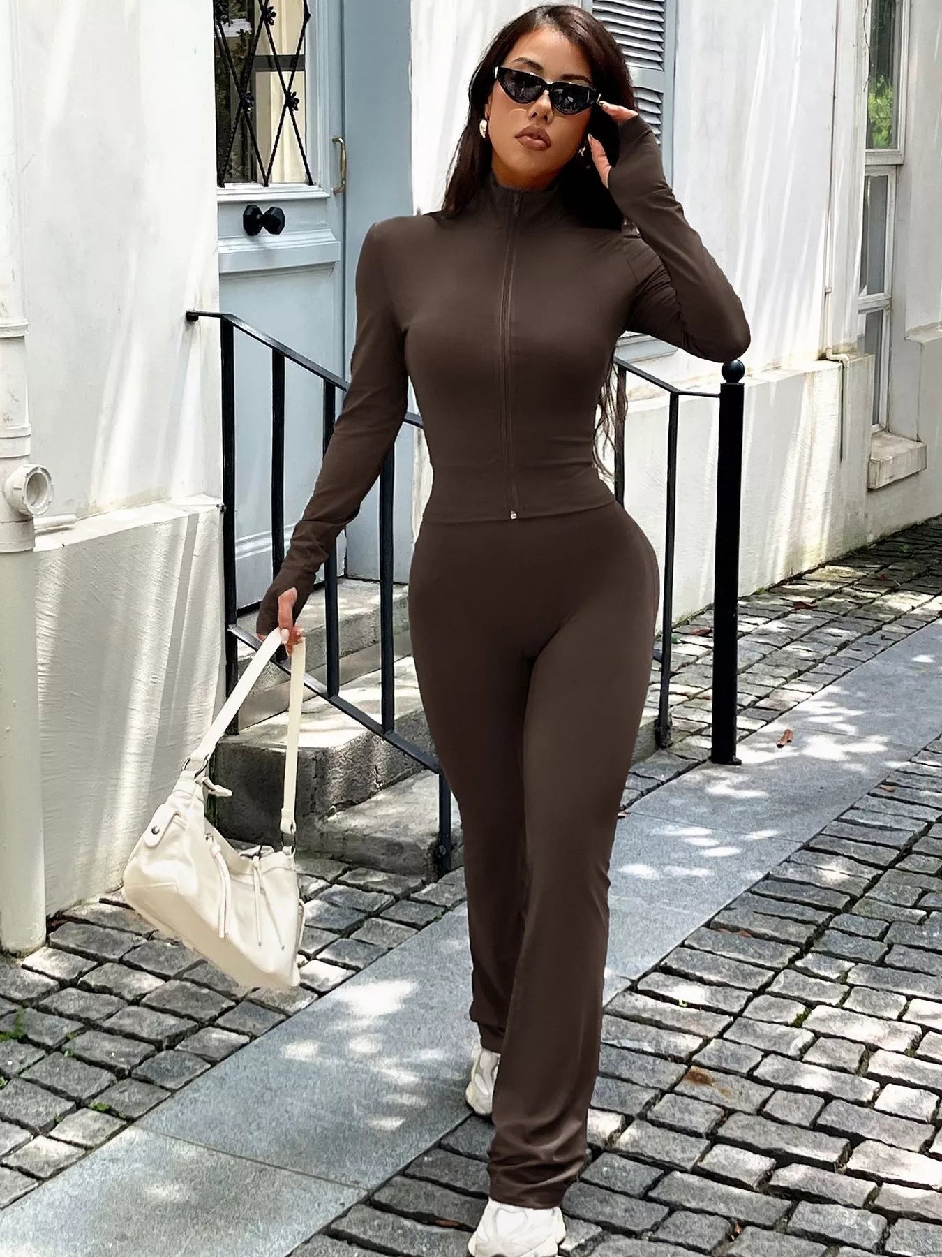 Brown zippered activewear set with mock neck and thumbhole sleeves.
