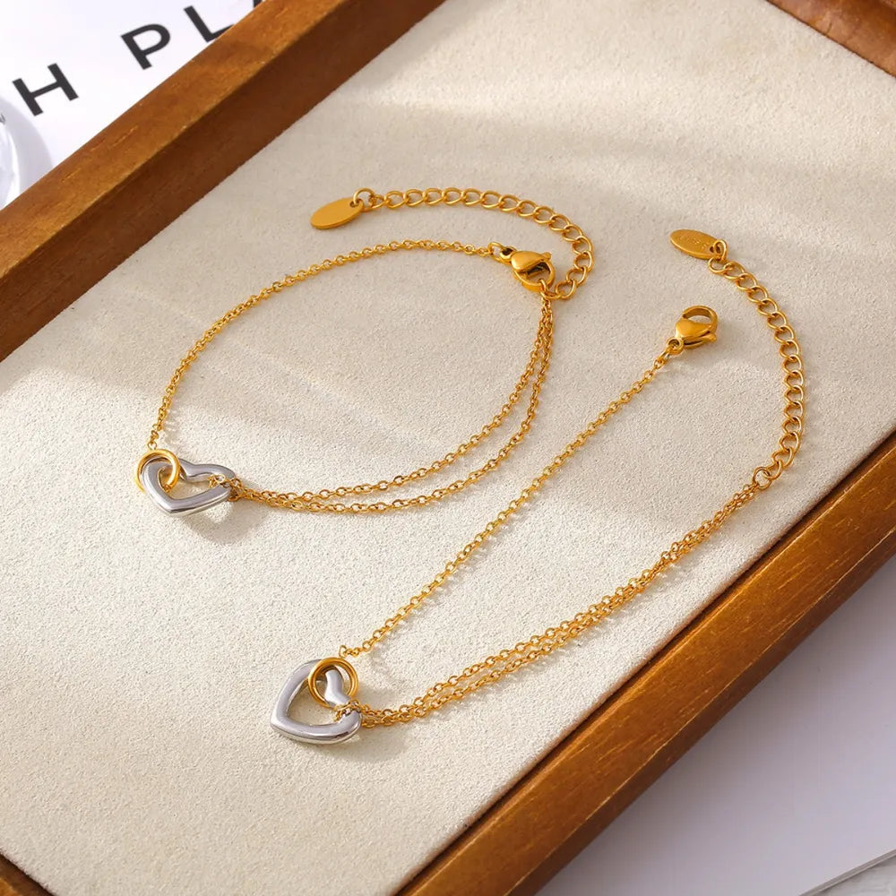 Gold two-tone heart charm chain bracelet with delicate double chains.