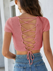 Crochet crop top in blush pink with short sleeves and a lace-up back detail.