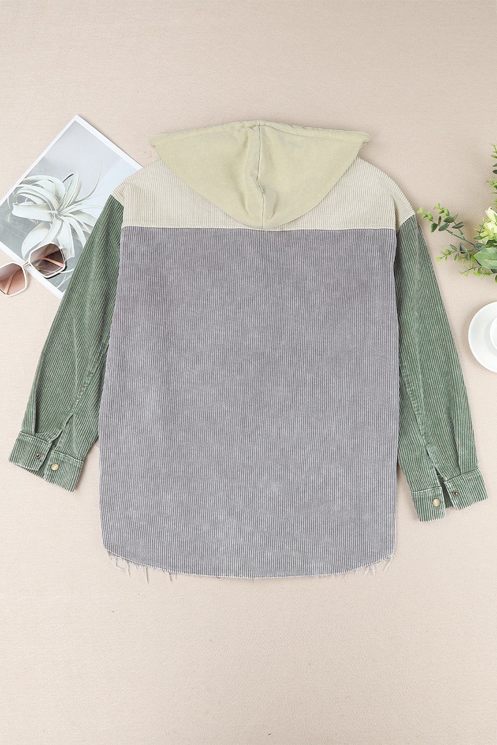 Colorblock corduroy hooded utility jacket in green, gray, and tan with frayed hem.