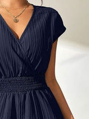 Navy textured wrap romper with V-neck, short sleeves, and smocked waist.
