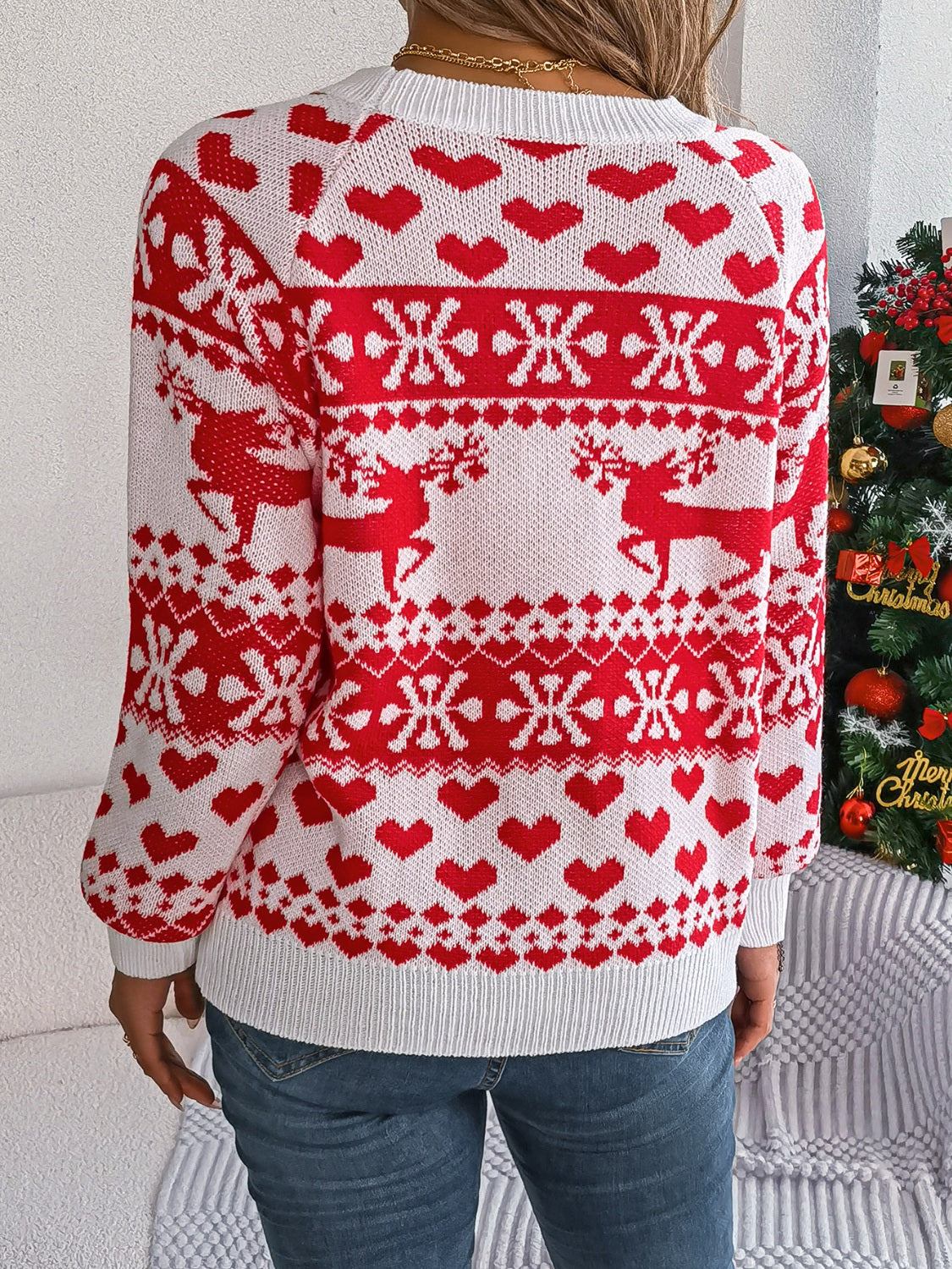 White acrylic sweater with red reindeer, snowflake, and heart jacquard pattern.