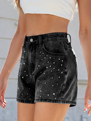 Black studded denim cutoff shorts with high waist and frayed hem.