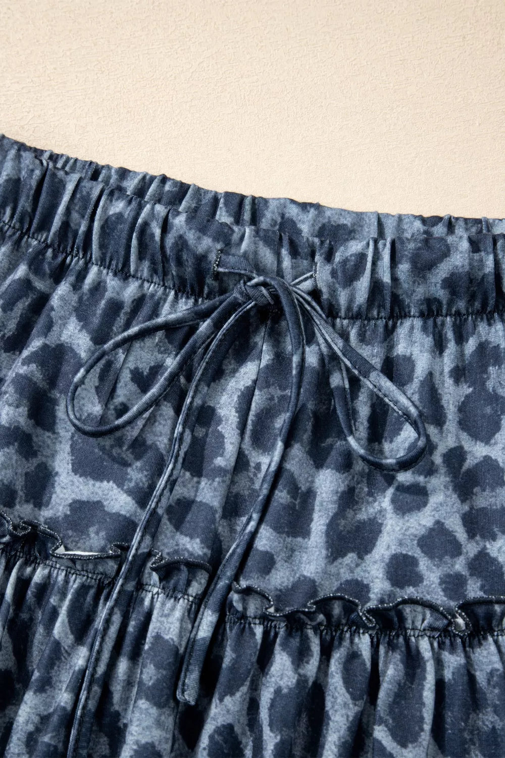 Maternity pants in dark navy with leopard print, elastic waist, drawstring, and ruffled hem.