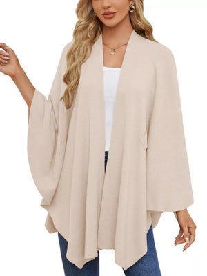 Eggshell knit cape top with draped elegance and wide sleeves, worn open over a white tank.