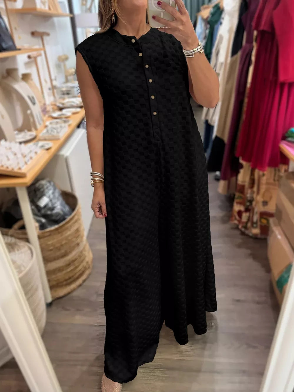 Black textured wide-leg jumpsuit with button-front and sleeveless design.