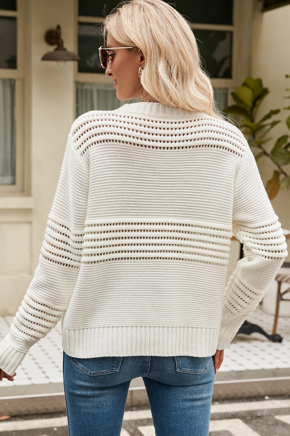 Cream open-knit mock neck sweater with horizontal openwork details and ribbed cuffs.