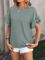 Sage green textured blouse with flutter sleeves and crew neck, styled with white shorts.