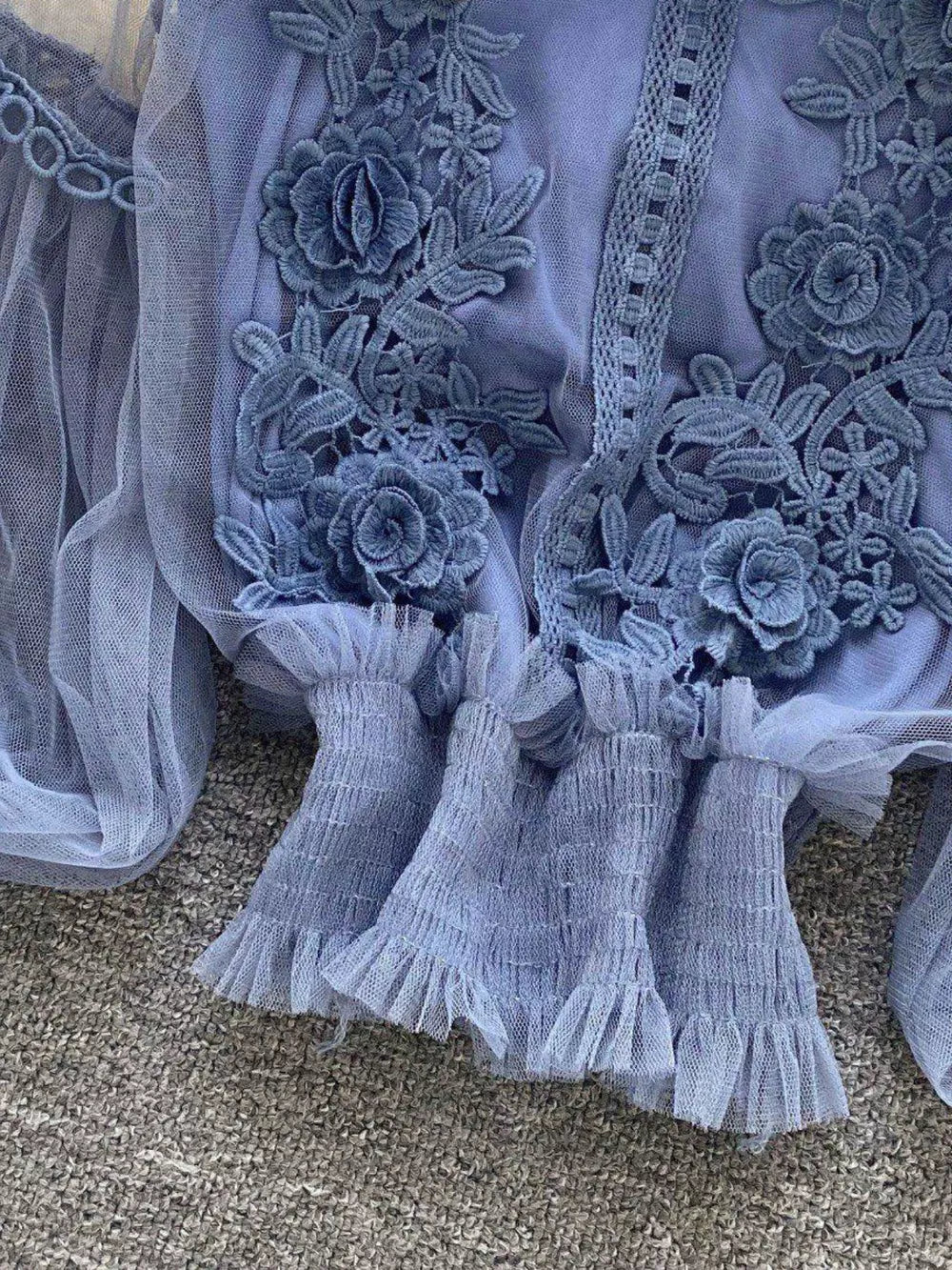 Blue lace blouse with floral embroidery and ruffled mesh sleeves.