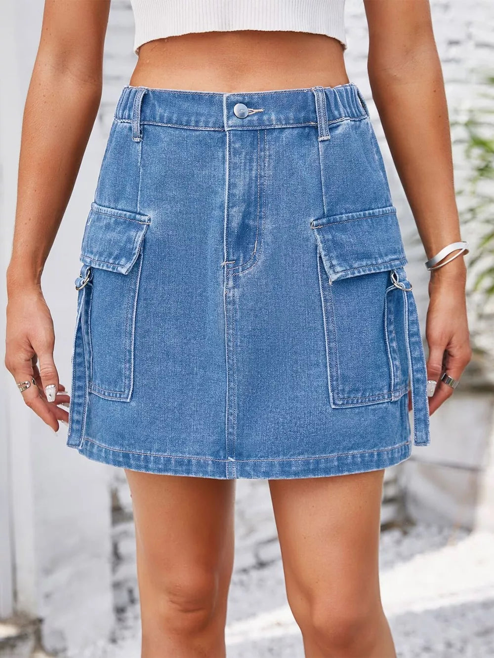Denim cargo skirt in Dusty Blue with utility pockets and metal ring details.