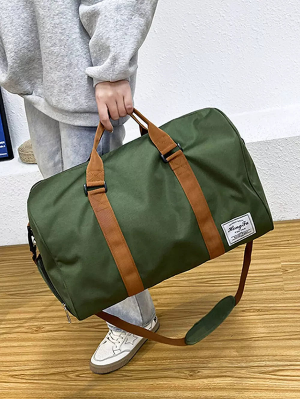 Green Oxford cloth duffel bag with brown straps and a white label.