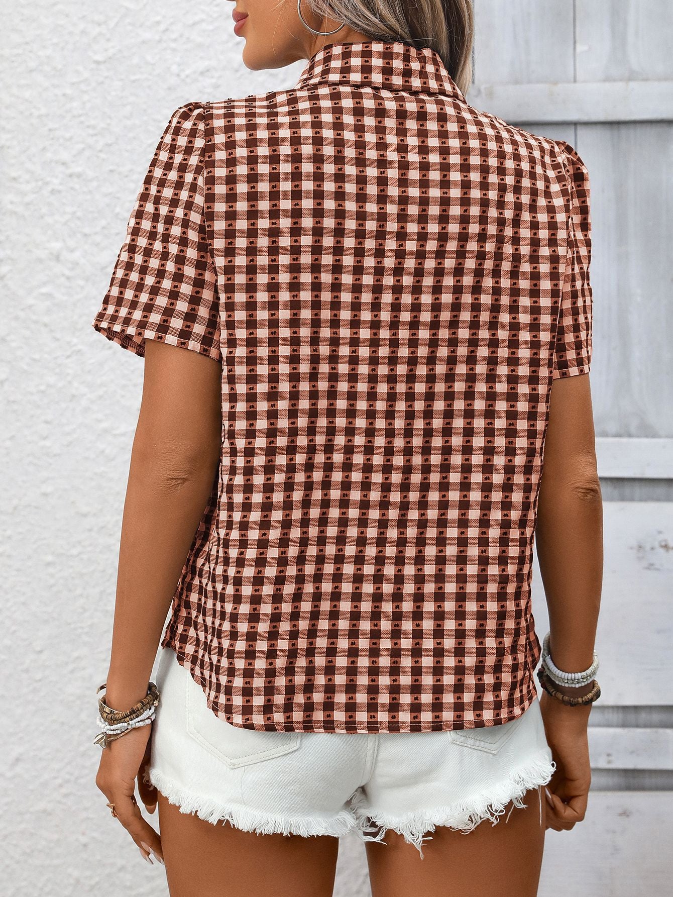 Rust red gingham button-up short-sleeve shirt with textured dots, styled with white denim shorts.