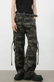 Wide-leg camo cargo pants with belt detail and tie straps in green camouflage.