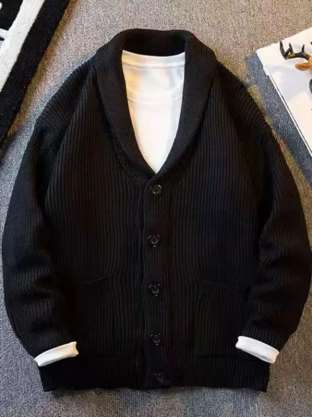 Black ribbed button-front cardigan with shawl collar and pockets, worn over a white t-shirt.