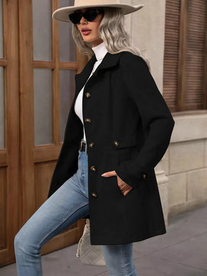Black button-up trench coat with cinched waist and gold buttons, worn with jeans.