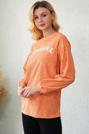Orange corduroy sweatshirt with white "Thankful" graphic, relaxed fit, long sleeves.