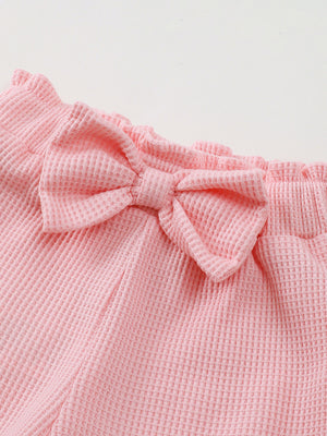 Pink waffle knit baby shorts with ruffled waist and bow detail