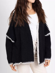 Black oversized cardigan with white contrast trim and textured knit.