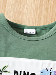 Green cotton baby tee with dinosaur embroidery and white panel detail.