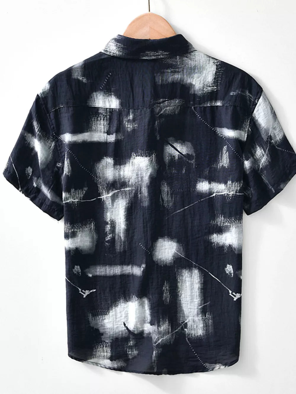 Men's black short sleeve polo with abstract print and button-down collar.