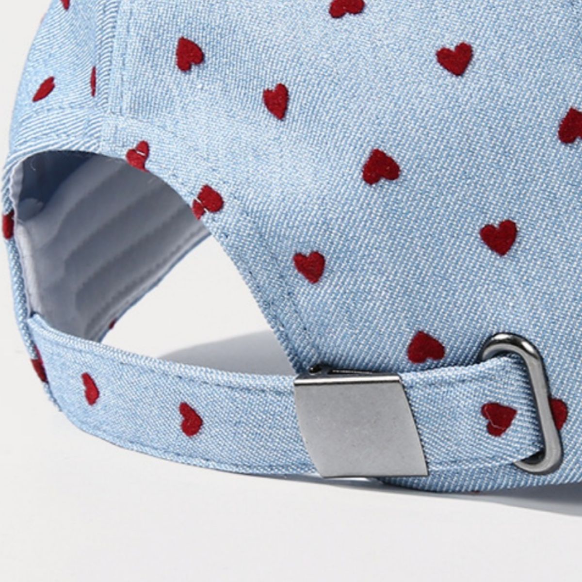 Sky blue baseball cap with red heart pattern and metal buckle detail.