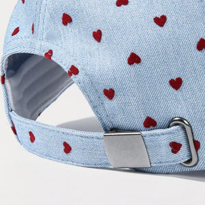 Sky blue baseball cap with red heart pattern and metal buckle detail.
