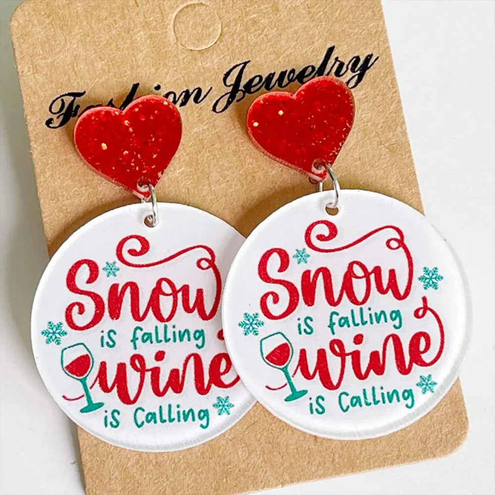 Festive acrylic drop earrings with red glitter hearts and round discs saying Snow is Falling Wine is Calling.