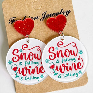 Festive acrylic drop earrings with red glitter hearts and round discs saying Snow is Falling Wine is Calling.